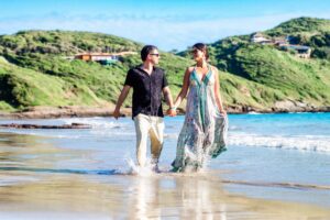 Casal caminhando na praia de Búzios em ensaio fotográfico romântico