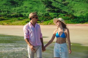 Casal caminhando na praia de Búzios em ensaio fotográfico romântico